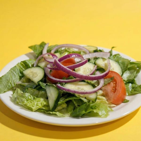 A fresh garden salad with lettuce, cucumber, tomato, and red onion on a white plate.